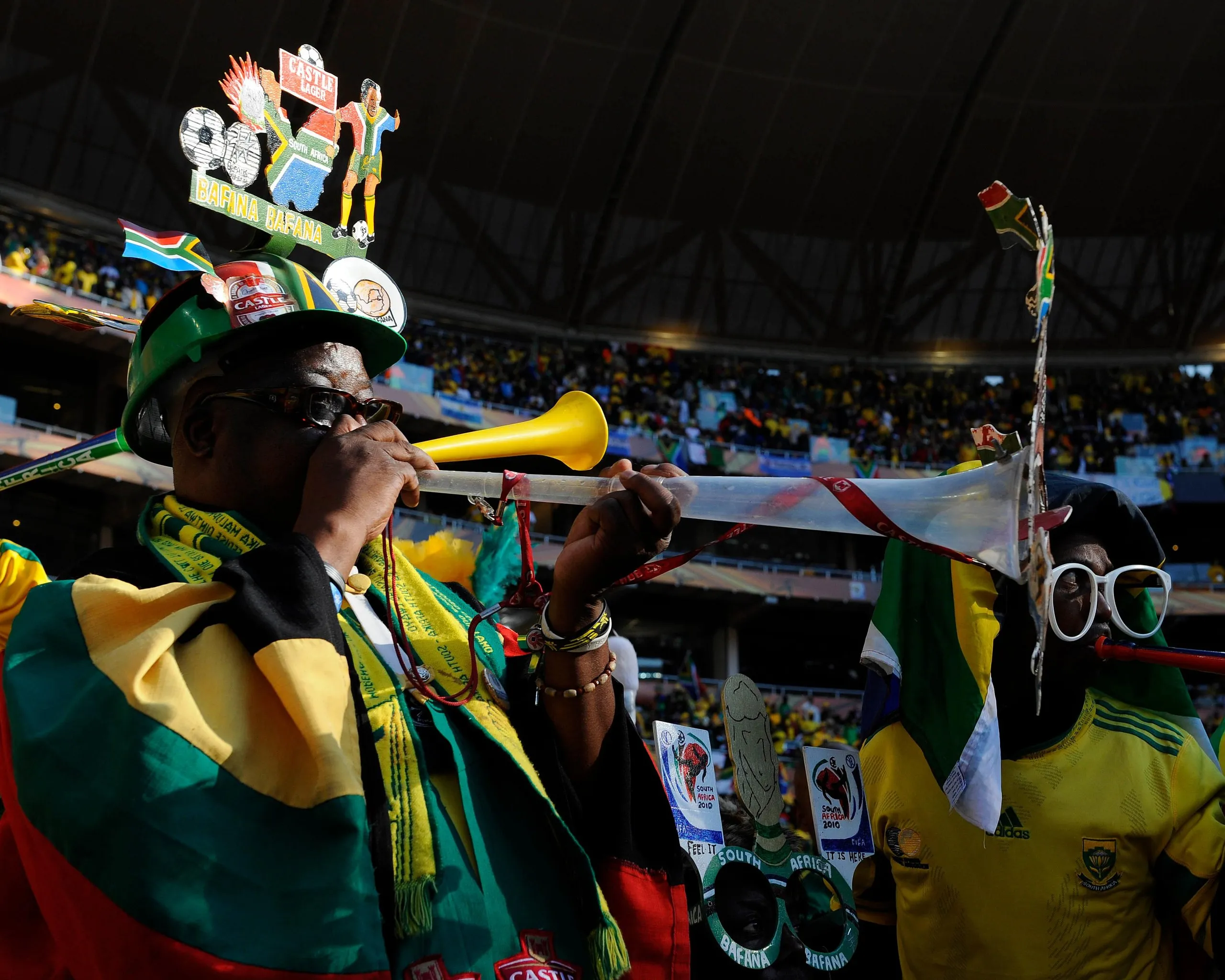 South Africa fans, wearing team jerseys, scarves, sunglasses and custom-made hats, blow vuvuzelas before their team play Mexico in the opening game of the 2010 World Cup in Johannesburg.